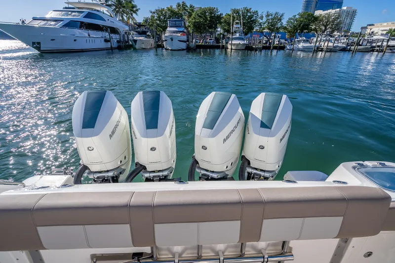 Slide: The Image of 2026 Boston Whaler 420 Outrage with four Mercury outboard engines docked in a marina. - 61