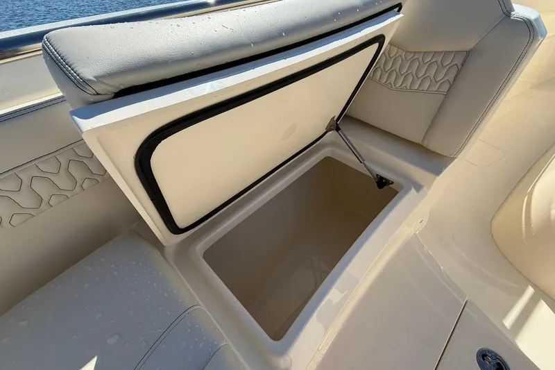 Slide: The Image of Open storage compartment on 2026 Scout 288 LXF boat, featuring cushioned seating. - 10