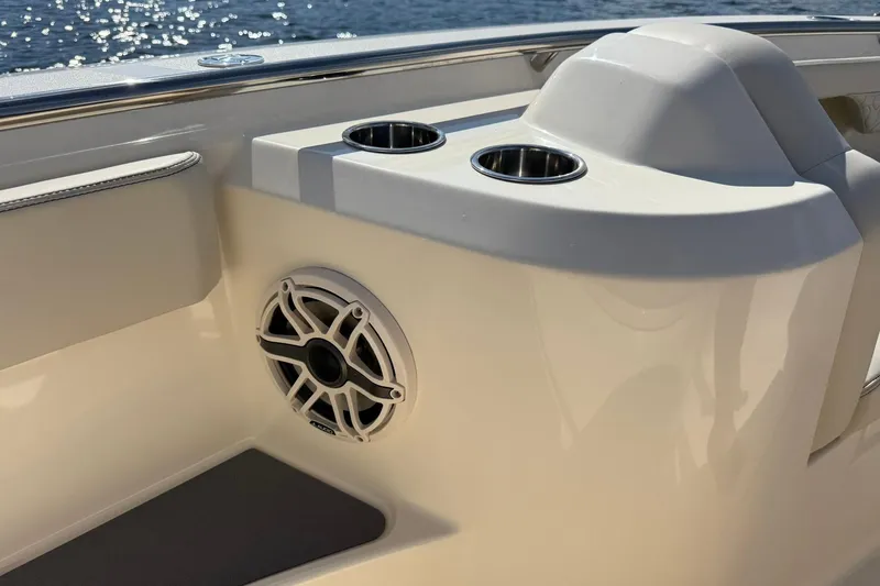 Slide: The Image of 2026 Scout 288 LXF boat interior with speaker and cup holders by the water. - 13