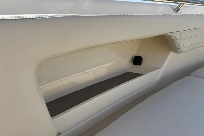 Slide: The Image of 2026 Scout 288 LXF boat interior storage compartment with cushioned seating. - 14