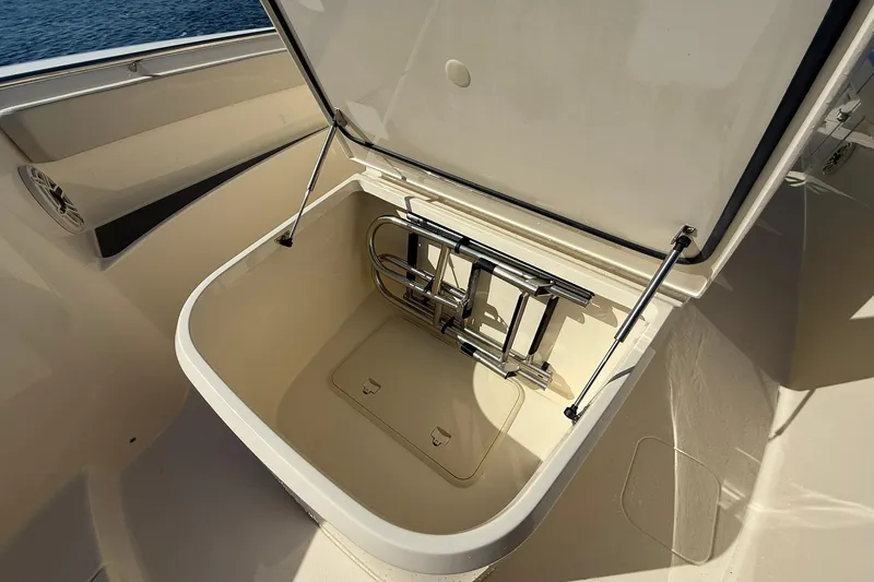 Slide: The Image of Open storage compartment on 2026 Scout 288 LXF boat, featuring a foldable ladder. - 16