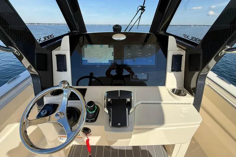 Slide: The Image of 2026 Scout 288 LXF boat helm with advanced navigation system and steering wheel on open water. - 28