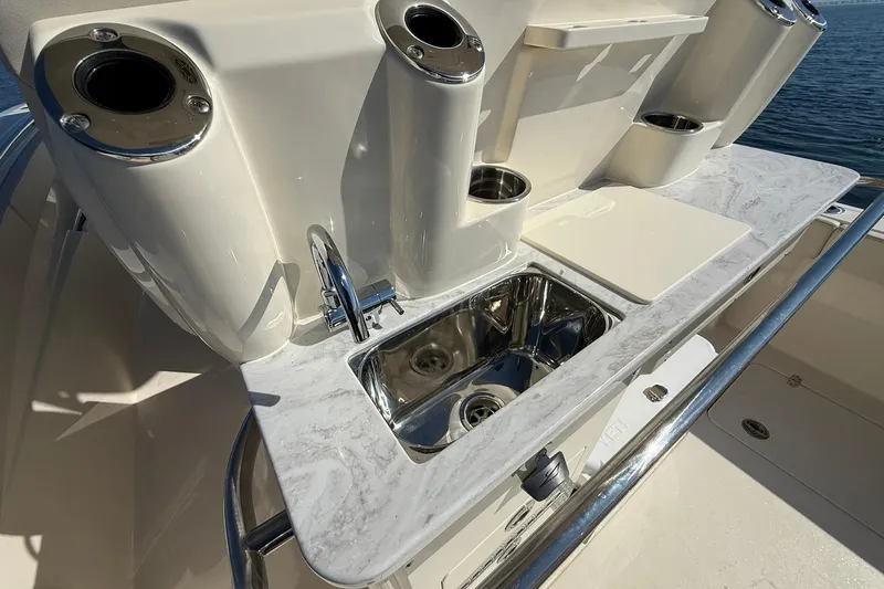 Slide: The Image of 2026 Scout 288 LXF boat sink and countertop with cup holders, on a sunny day. - 33