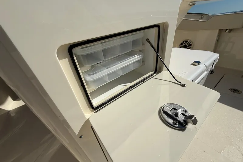 Slide: The Image of Storage compartment on 2026 Scout 288 LXF boat, featuring organized plastic containers. - 35