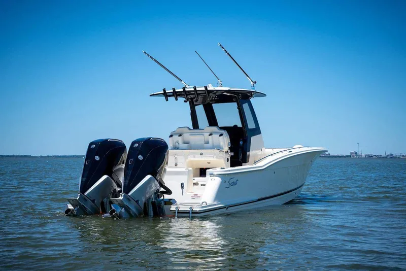 Slide: The Image of 2026 Scout 288 LXF boat cruising on a calm lake with a person at the helm. - 4
