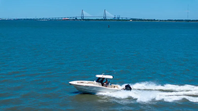 Slide: The Image of 2026 Scout 288 LXF boat cruising on a calm lake with a clear sky. - 6