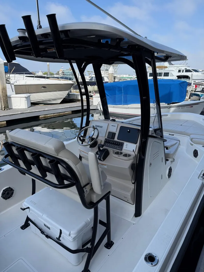 Slide: The Image of 2024 Boston Whaler 250 Dauntless boat interior with helm and seating at marina. - 3