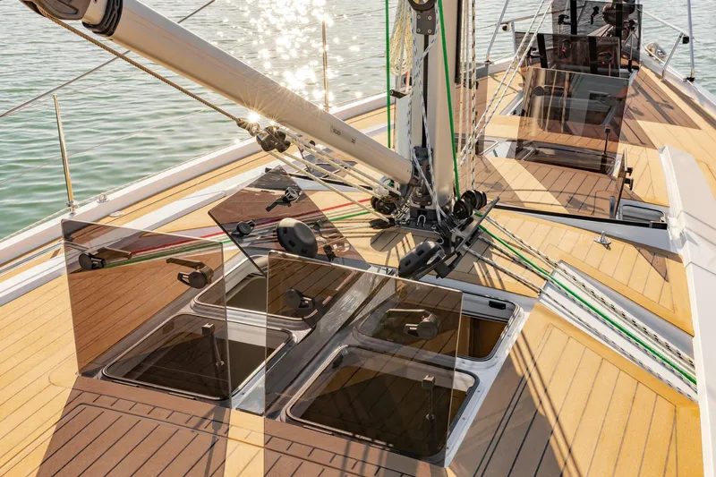 Slide: The Image of 2023 Hanse 460 yacht deck with open hatches and rigging, sunlight reflecting on water. - 10
