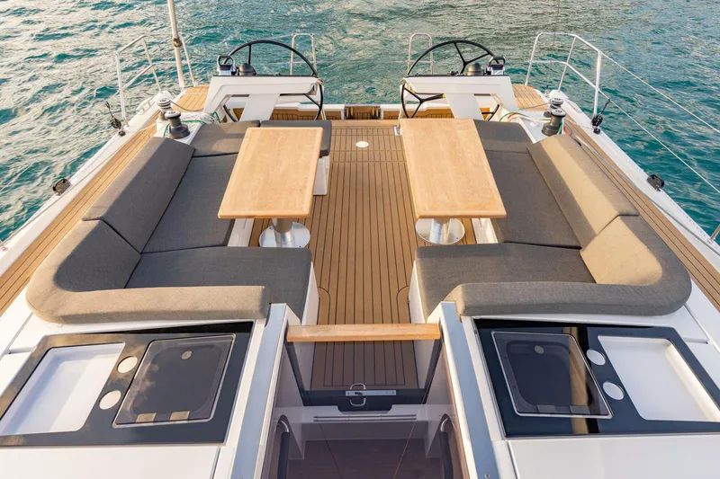 Slide: The Image of 2023 Hanse 460 yacht deck with seating, tables, and dual steering wheels on the water. - 12