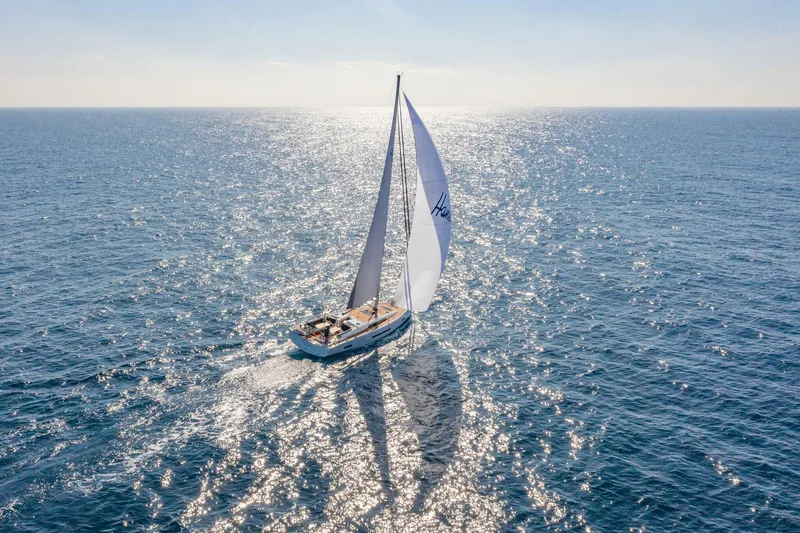 Slide: The Image of 2023 Hanse 460 sailboat gliding on sparkling ocean waters under clear skies. - 2