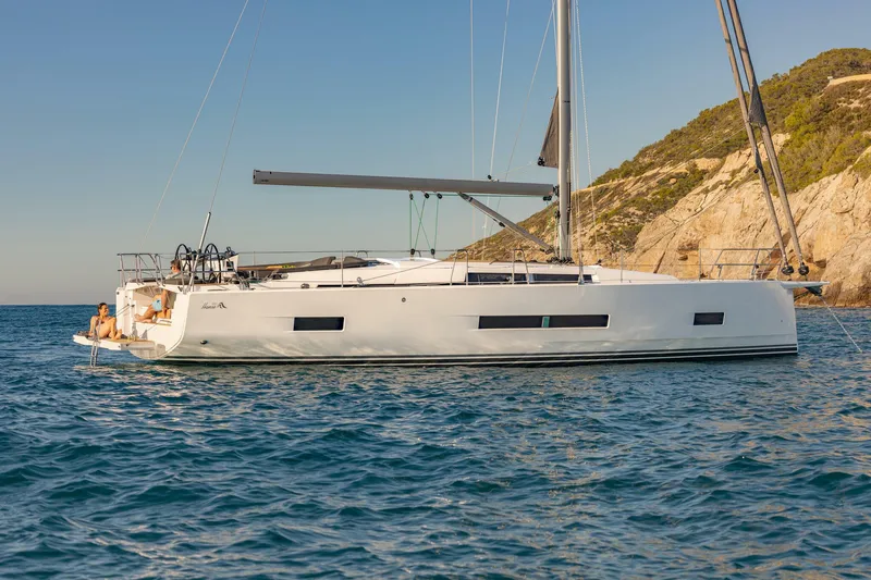 Slide: The Image of 2023 Hanse 460 yacht sailing near rocky coastline under clear blue sky. - 7