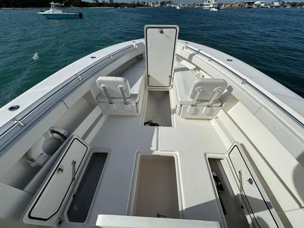 Slide: The Image of 2015 Invincible 39 Open Fisherman boat interior with open storage compartments on calm water. - 13