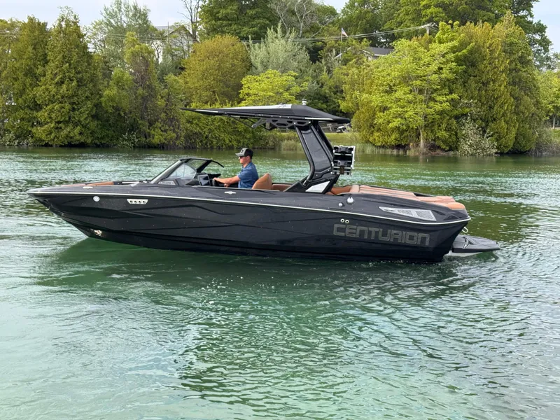 Slide: The Image of 2025 Centurion NV 213 boat cruising on a serene lake with lush green trees. - 5