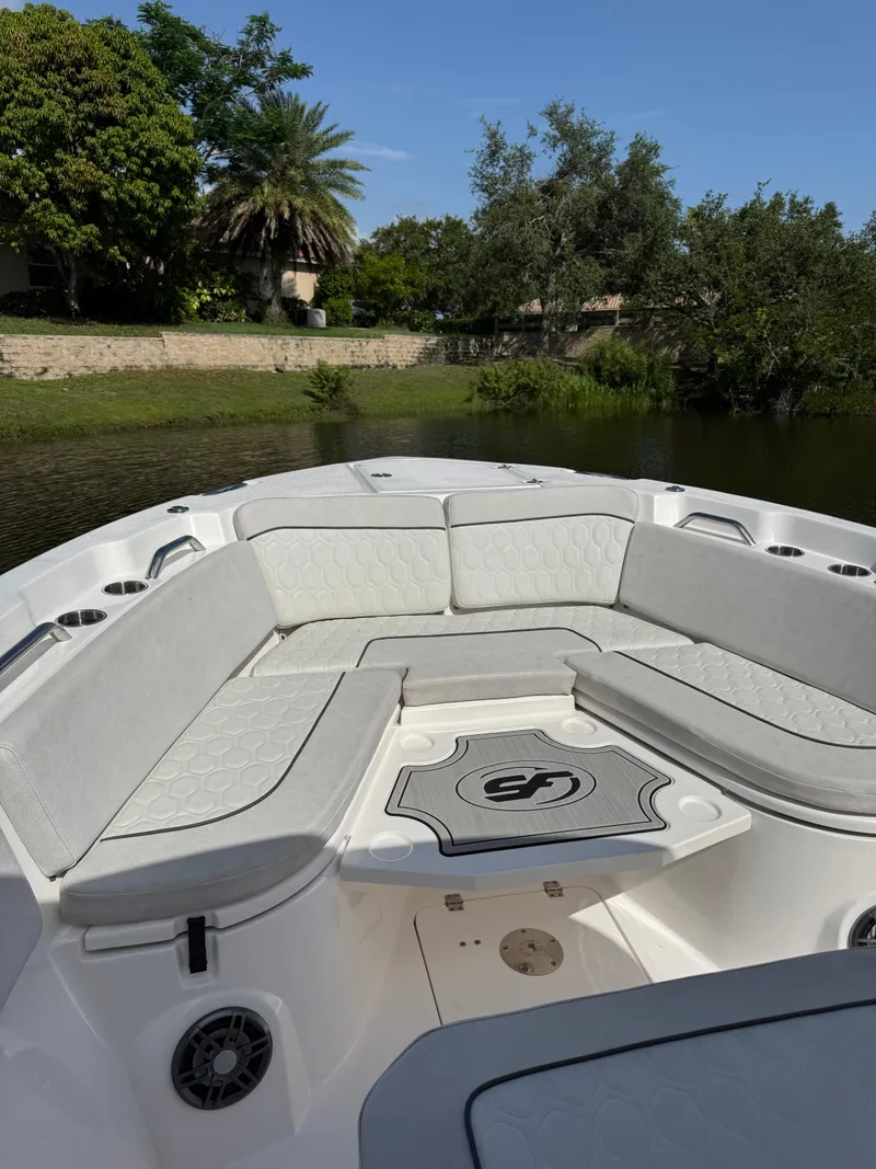 Slide: The Image of 2023 Sea Fox 268 Commander boat interior with cushioned seating, surrounded by lush greenery. - 10