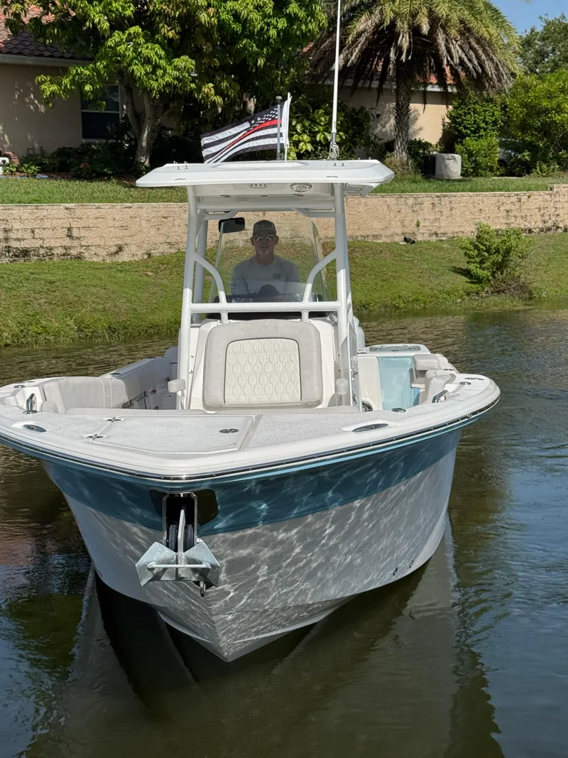 Slide: The Image of 2023 Sea Fox 268 Commander boat on water, with trees and house in background. - 2