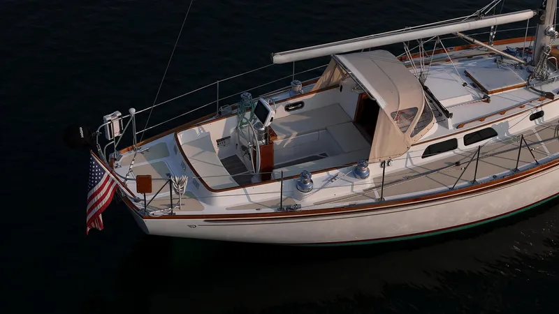 Slide: The Image of 1988 Hinckley Sou'wester 42 sailboat with American flag, docked on calm water. - 13