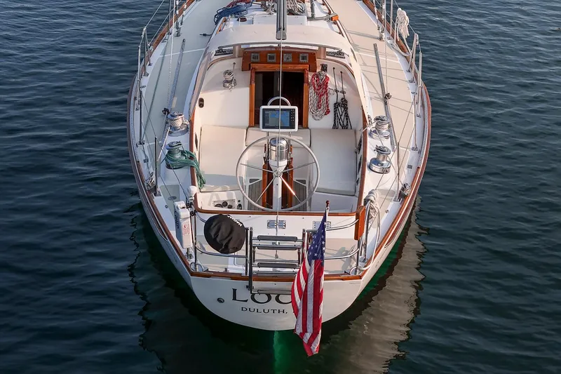 Slide: The Image of 1988 Hinckley Sou'wester 42 sailboat on calm water, rear view with American flag. - 15