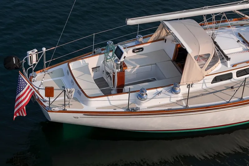 Slide: The Image of 1988 Hinckley Sou'wester 42 sailboat with American flag, docked on calm water. - 16