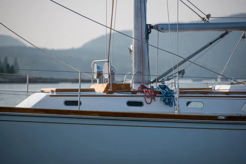 Slide: The Image of 1988 Hinckley Sou'wester 42 sailboat with ropes and mast, docked near mountains. - 18