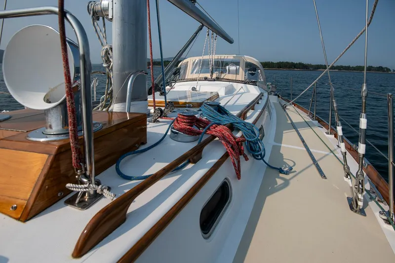 Slide: The Image of 1988 Hinckley Sou'wester 42 sailboat deck with ropes and wooden details on calm water. - 25