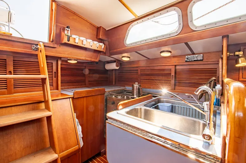 Slide: The Image of Interior of 1988 Hinckley Sou'wester 42 sailboat, featuring wooden cabinetry and stainless steel sink. - 43