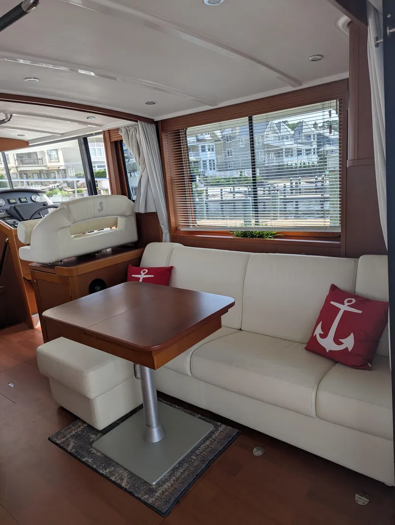 Slide: The Image of Interior of 2019 Beneteau Swift Trawler 44 with white sofa and wooden table. - 12