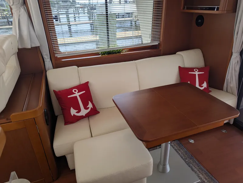 Slide: The Image of Interior of 2019 Beneteau Swift Trawler 44 with anchor-themed cushions and wooden table. - 18