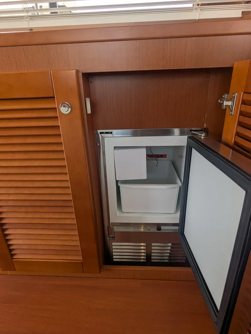 Slide: The Image of Beneteau Swift Trawler 44 (2019) interior with open mini fridge in wooden cabinet. - 21