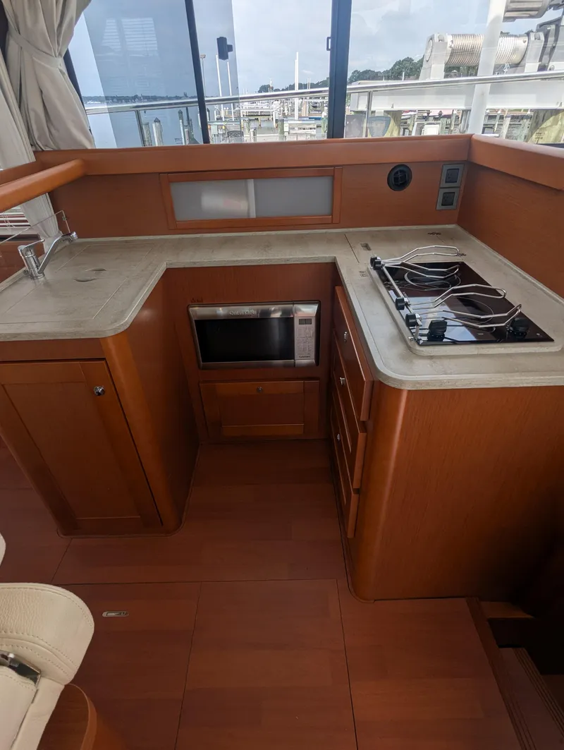 Slide: The Image of 2019 Beneteau Swift Trawler 44 kitchen with stove, microwave, and wooden cabinetry. - 23
