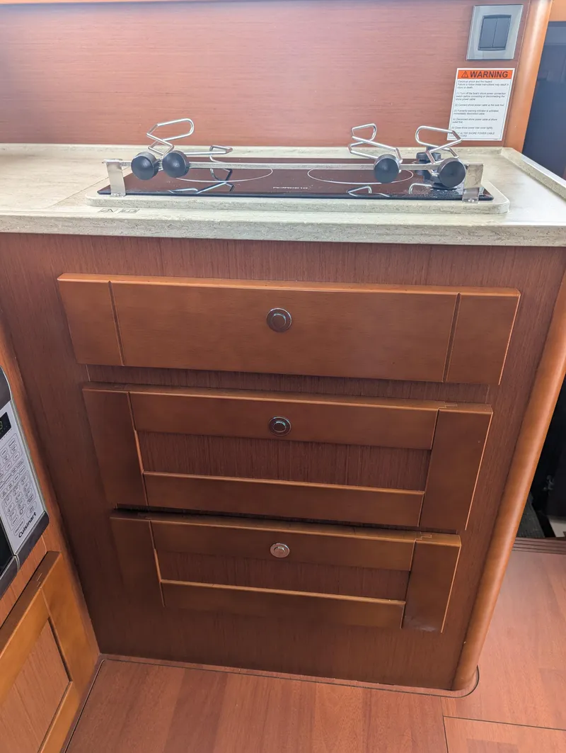 Slide: The Image of 2019 Beneteau Swift Trawler 44 kitchen with stove and wooden cabinetry. - 25