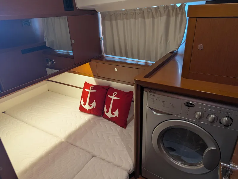 Slide: The Image of Cozy cabin interior of 2019 Beneteau Swift Trawler 44 with bed, anchor pillows, and washing machine. - 42