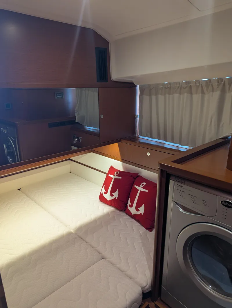 Slide: The Image of Cozy cabin interior of 2019 Beneteau Swift Trawler 44 with bed, anchor pillows, and washer. - 44