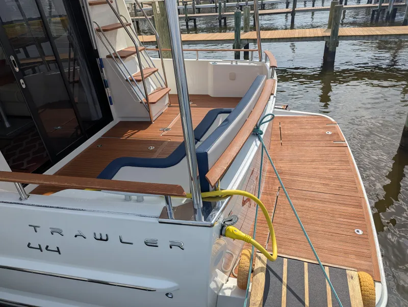 Slide: The Image of 2019 Beneteau Swift Trawler 44 docked, showcasing elegant wooden deck and seating area. - 5