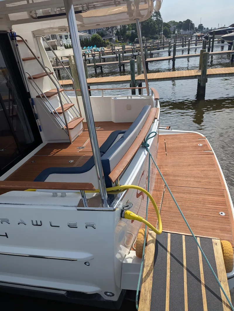 Slide: The Image of 2019 Beneteau Swift Trawler 44 docked, showcasing elegant wooden deck and seating area. - 6