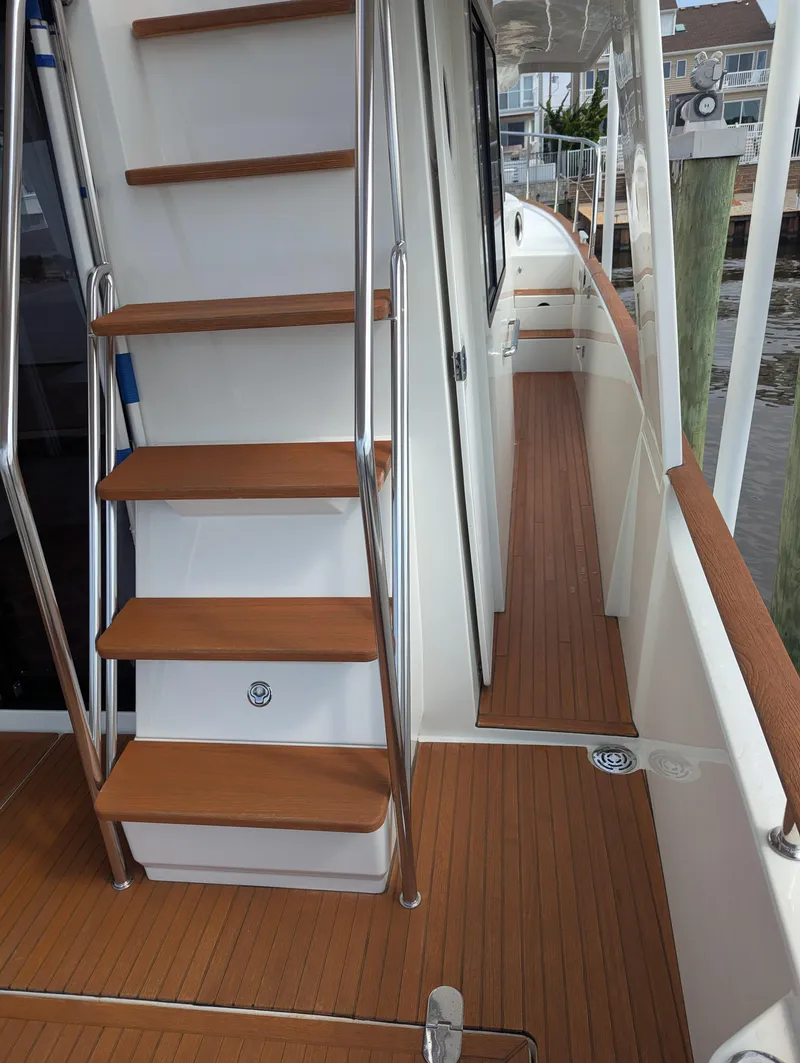 Slide: The Image of 2019 Beneteau Swift Trawler 44 deck with wooden stairs and railing. - 7