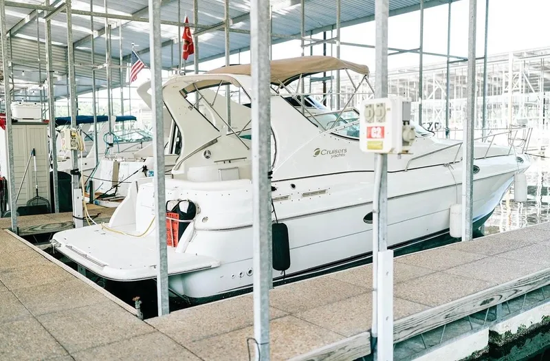 Slide: The Image of 2001 Cruisers Yachts 3075 Express docked in a marina, covered by a metal roof. - 17