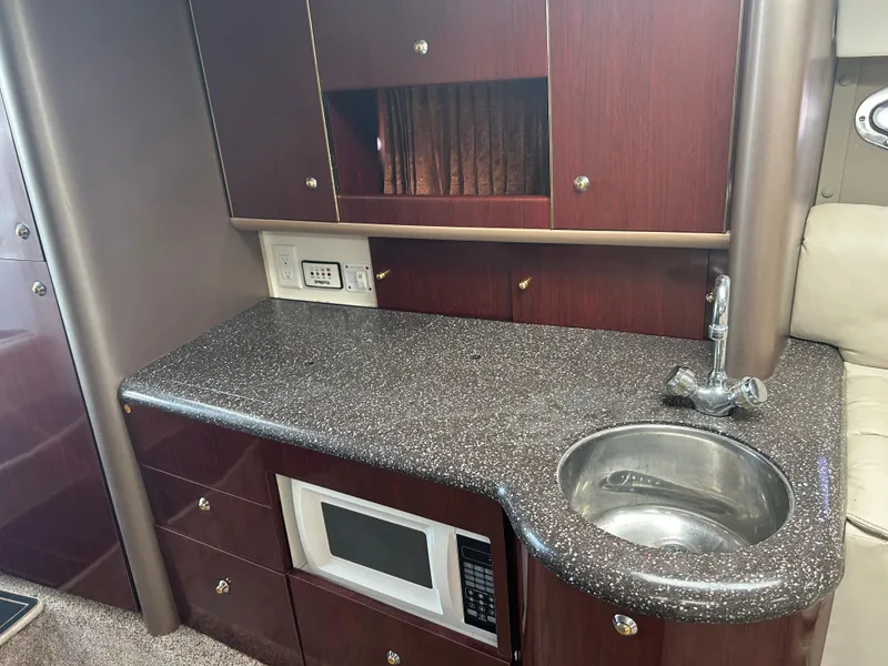 Slide: The Image of 2004 Formula 400 SS yacht interior with kitchenette, featuring sink, microwave, and dark wood cabinetry. - 27