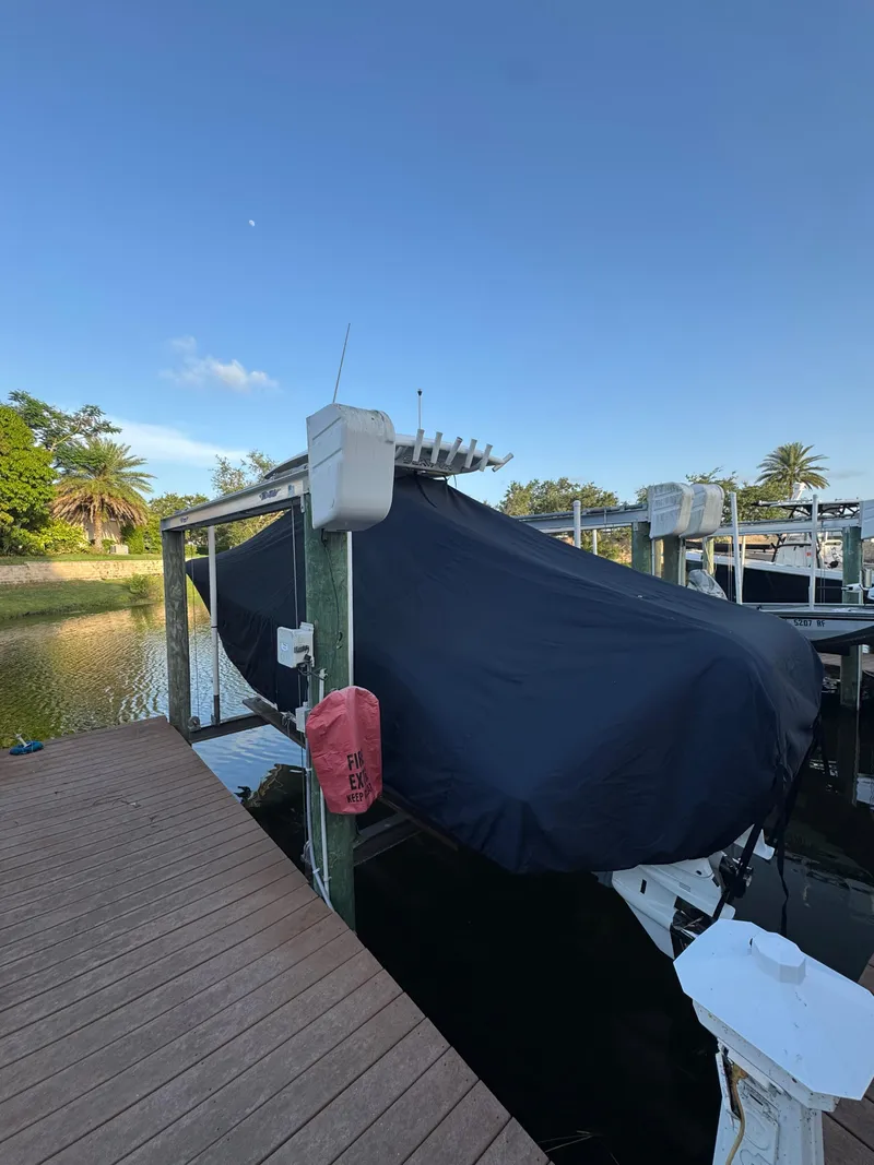 Slide: The Image of Covered 2023 Sea Fox 268 Commander boat on a dock lift under clear blue sky. - 6