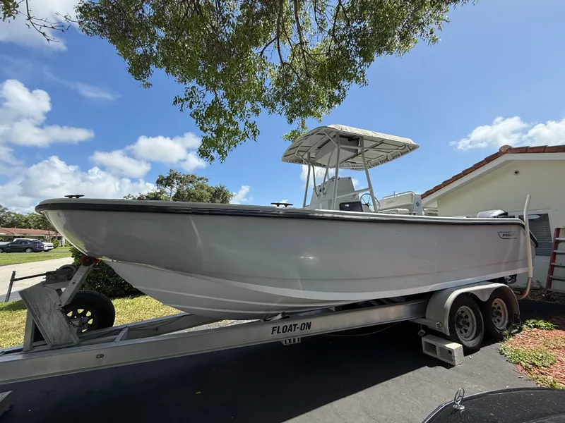 Slide: The Image of 2005 Boston Whaler 260 Outrage boat on trailer under tree, clear sky background. - 13