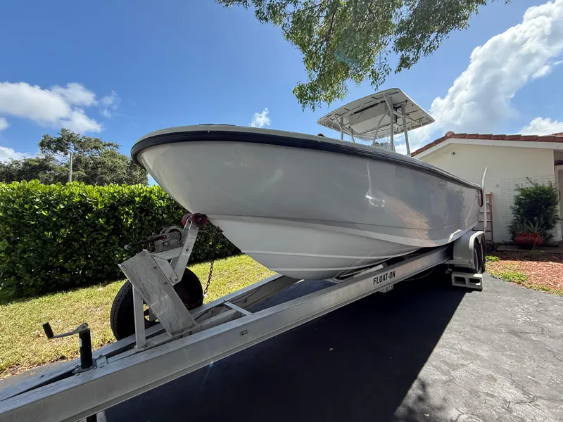 Slide: The Image of 2005 Boston Whaler 260 Outrage boat on trailer, parked in driveway under clear blue sky. - 14