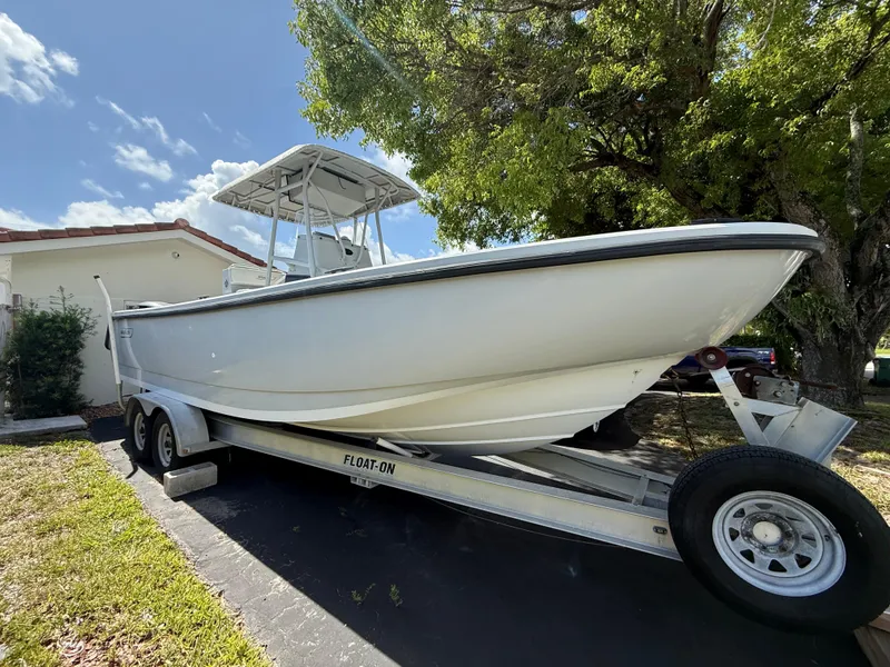 Slide: The Image of 2005 Boston Whaler 260 Outrage boat on trailer, parked near house and trees. - 2