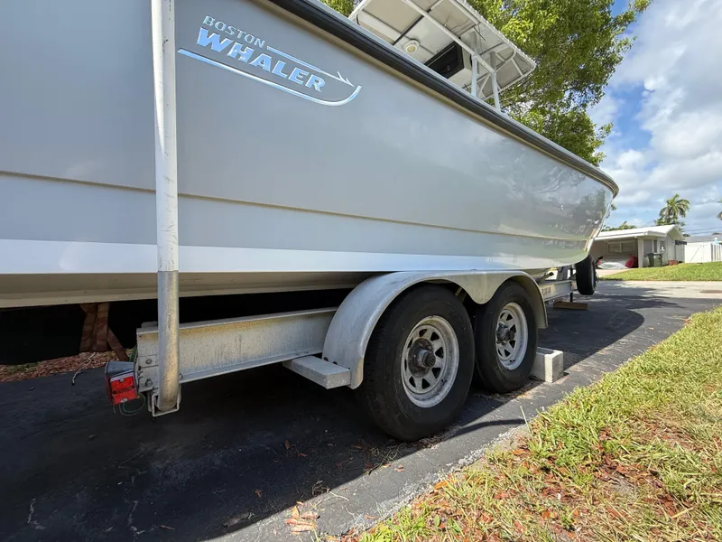 Slide: The Image of 2005 Boston Whaler 260 Outrage on trailer, parked in driveway under blue sky. - 22