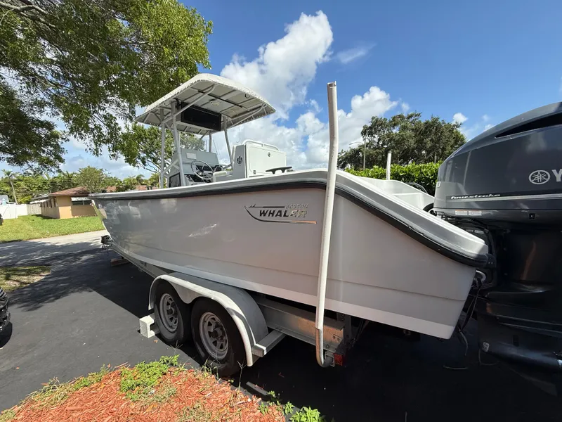 Slide: The Image of 2005 Boston Whaler 260 Outrage boat on trailer, parked outdoors under a clear blue sky. - 27