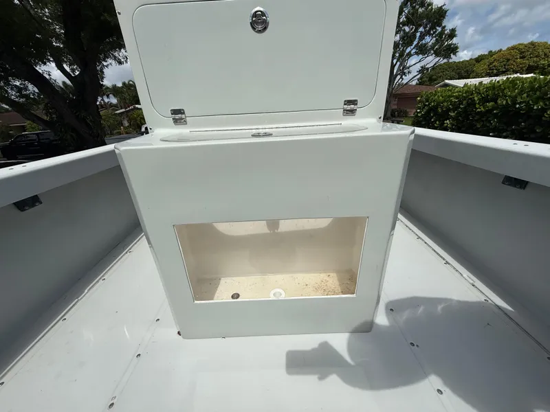 Slide: The Image of 2005 Boston Whaler 260 Outrage storage compartment, open lid, white interior, outdoor setting. - 34