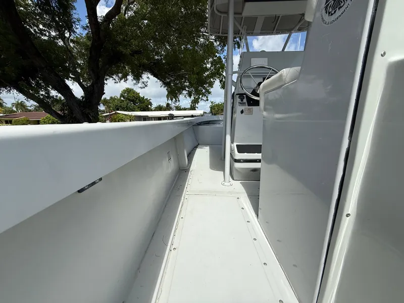 Slide: The Image of 2005 Boston Whaler 260 Outrage boat interior, featuring steering console and seating under a canopy. - 37