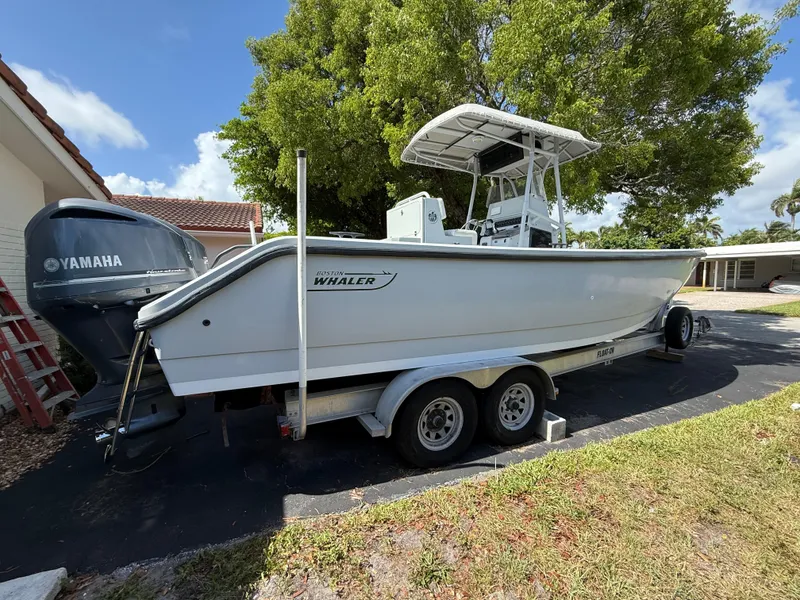 Slide: The Image of 2005 Boston Whaler 260 Outrage boat on trailer, parked outdoors near trees. - 4