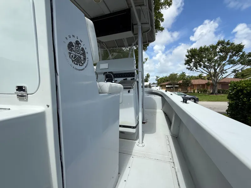 Slide: The Image of 2005 Boston Whaler 260 Outrage boat interior with console and seating, under a clear blue sky. - 44