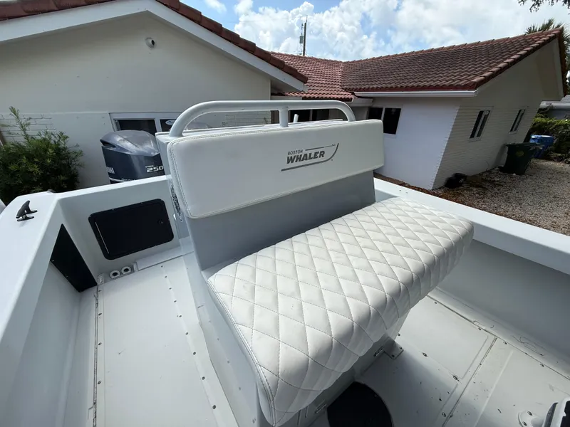 Slide: The Image of 2005 Boston Whaler 260 Outrage boat with white quilted seating, near a house. - 45