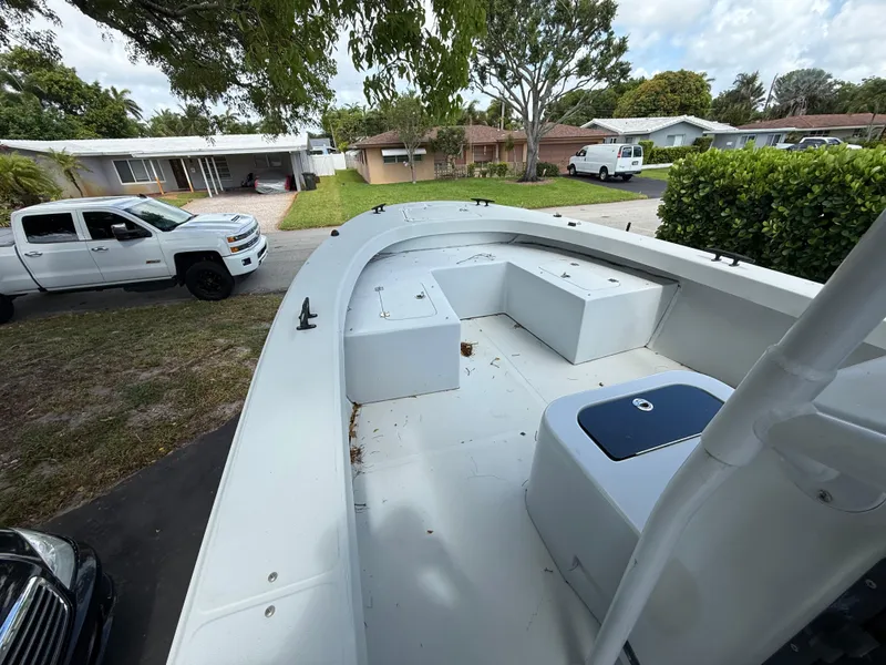 Slide: The Image of 2005 Boston Whaler 260 Outrage boat parked in residential driveway, surrounded by trees and vehicles. - 49