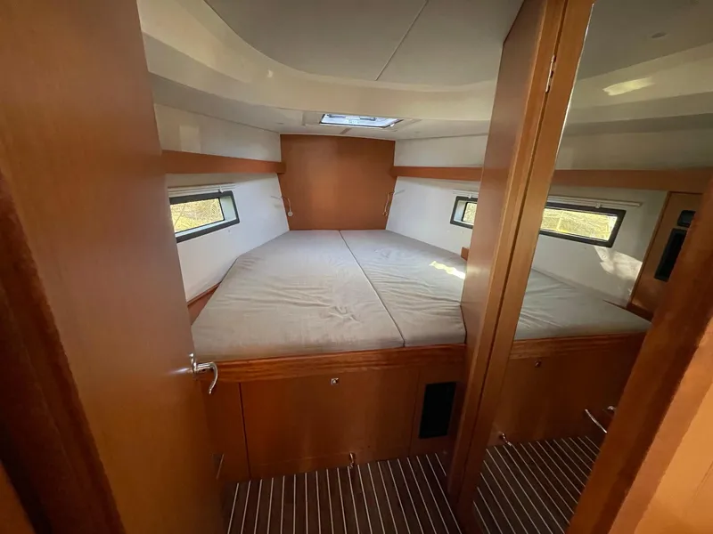 Slide: The Image of 2023 Bavaria C42 yacht cabin with double bed, wooden interior, and natural light. - 14